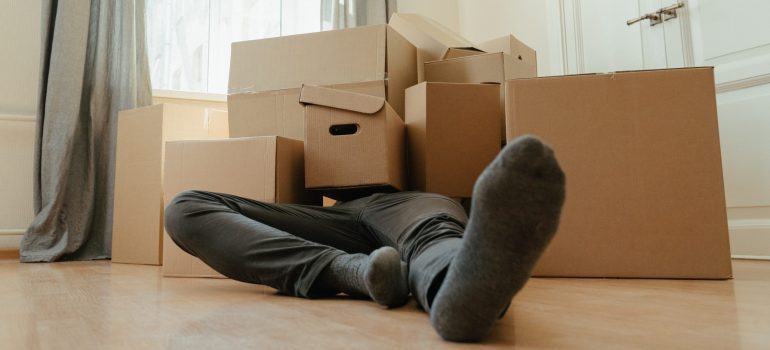 A man lying under a pile of boxes