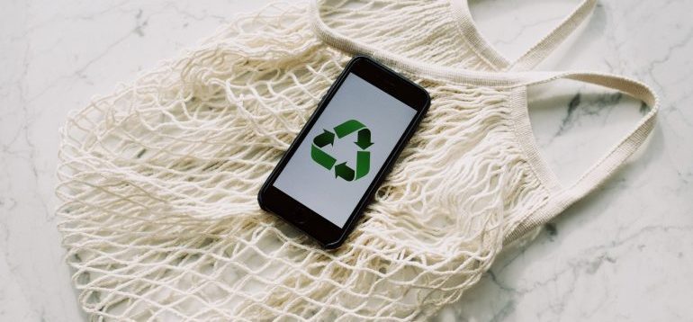 Mobile phone with green recycling sign and mesh bag