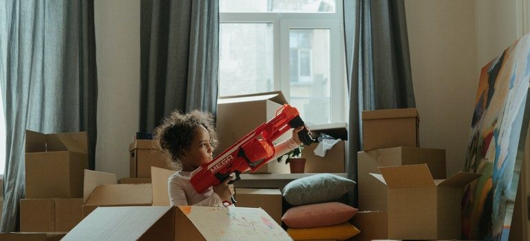 Kid in cardboard box playing with toy gun