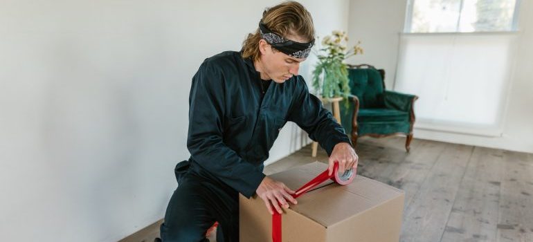 Mover taping a moving box.