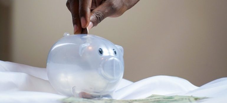 a person putting mney into a transparent piggy bank