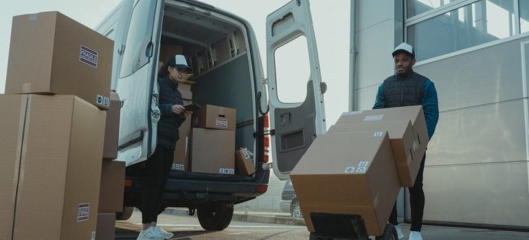 A man and a woman loading moving boxes into a white van
