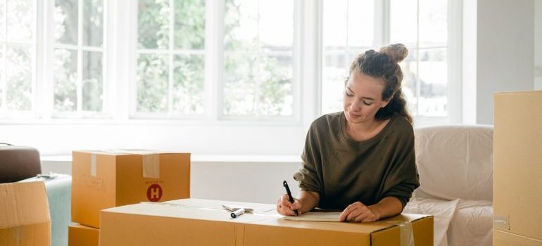 A woman writing on a moving box