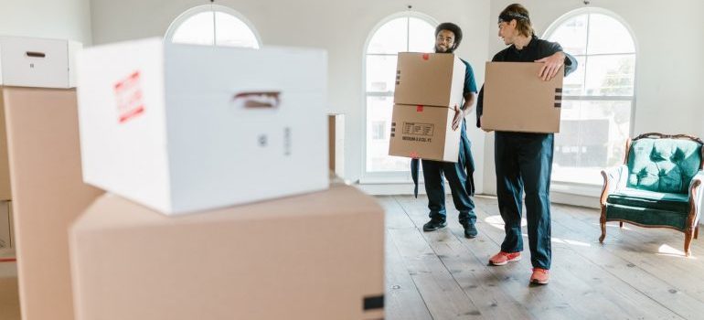 Two men holding boxes, movers can help you relocate from Glendale to Covina