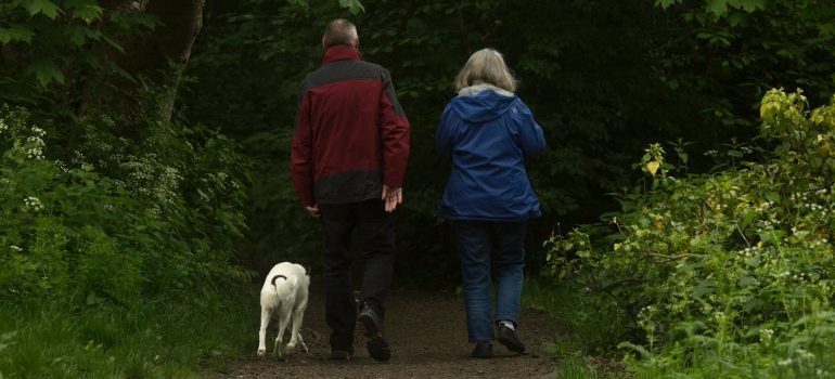 A man in red jacket and a woman in a blue jacket walking the dog