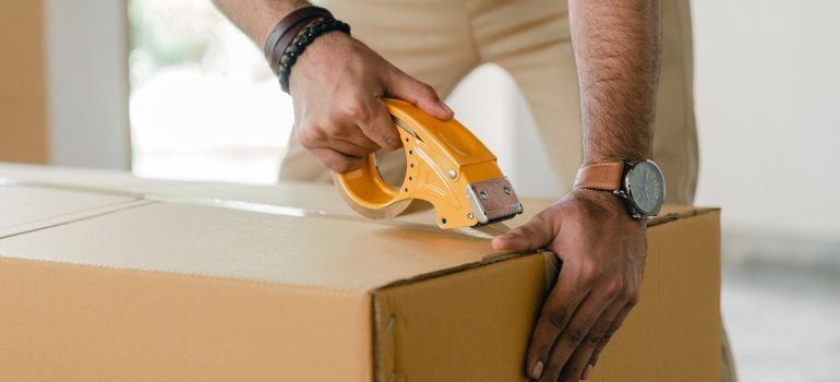 Man sealing a box with tape 